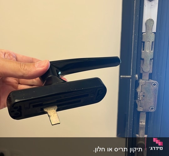 יד מחזיקה ידית חלון ליד מסגרת מתכת